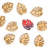 miniature monstera wooden leaf cut outs with one leaf painted red and purple