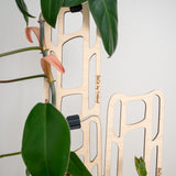 bella Wooden plant trellis with decorative ladder design, featuring a plant with green leaves and pink flowers.