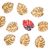 miniature monstera wooden leaf cut outs with one leaf painted red and purple 
