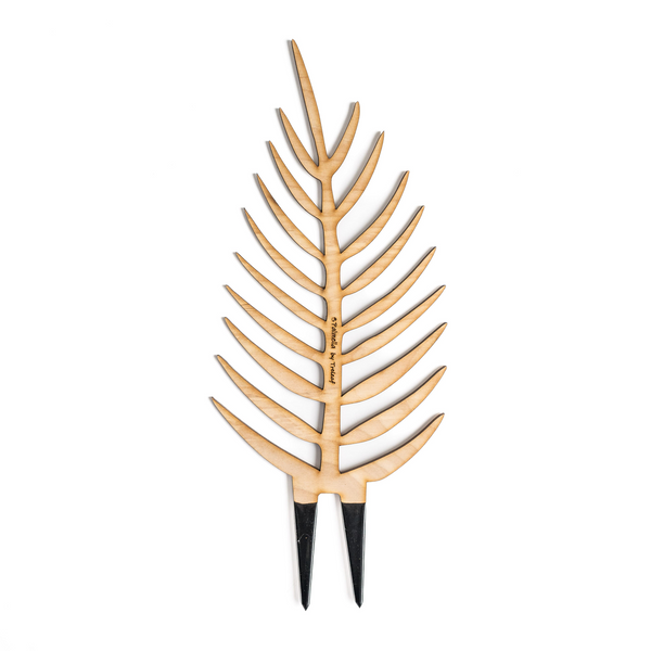 Wooden trellis shaped like a palm leaf with black stakes and engraved Palmella by treleaf